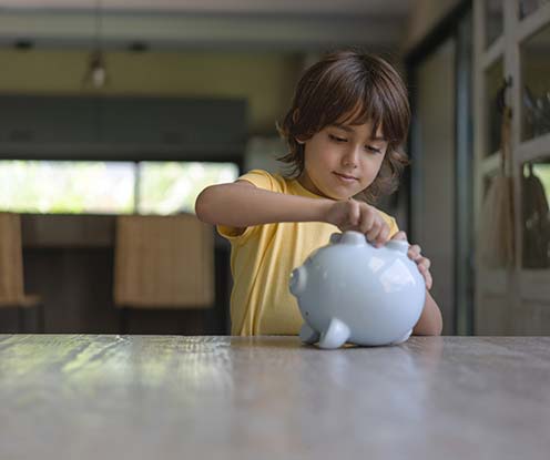 Little boy saving money in a piggy bank