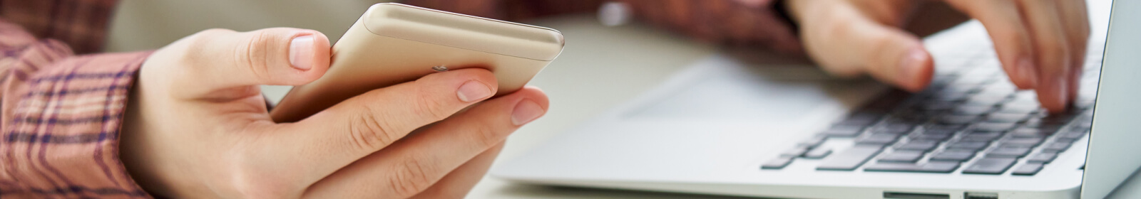 hands on a phone and computer