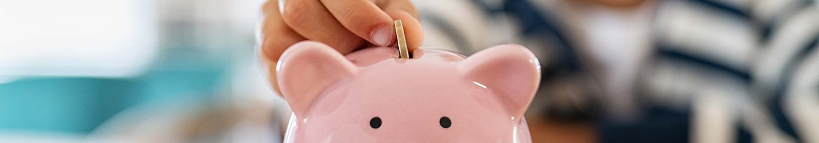 Kid dropping money in a piggy bank savings